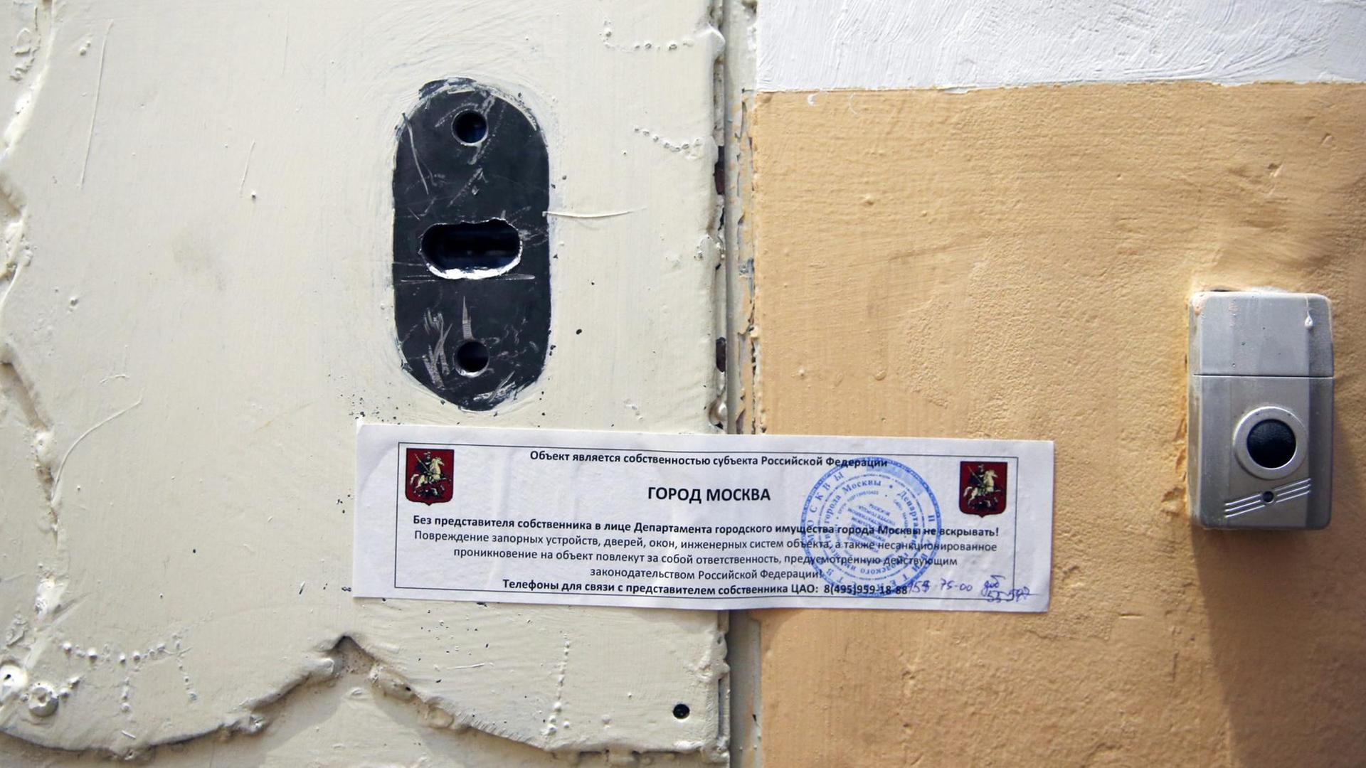 Nahaufnahme der Tür des Amnesty-International Büros in Moskau, die mit einem amtlichen Zettel in kyrillischer Schrift zugeklebt ist.