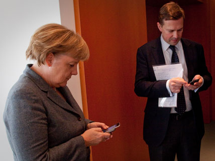 Bundeskanzlerin Angela Merkel (CDU) tippt am Montag neben ihrem Sprecher Steffen Seibert im Bundeskanzleramt in Berlin in ihr Handy.