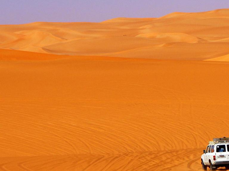 Geländefahrzeug fährt in den Sanddünen im Ubari Sandmeer, Sahara, Libyen, Afrika