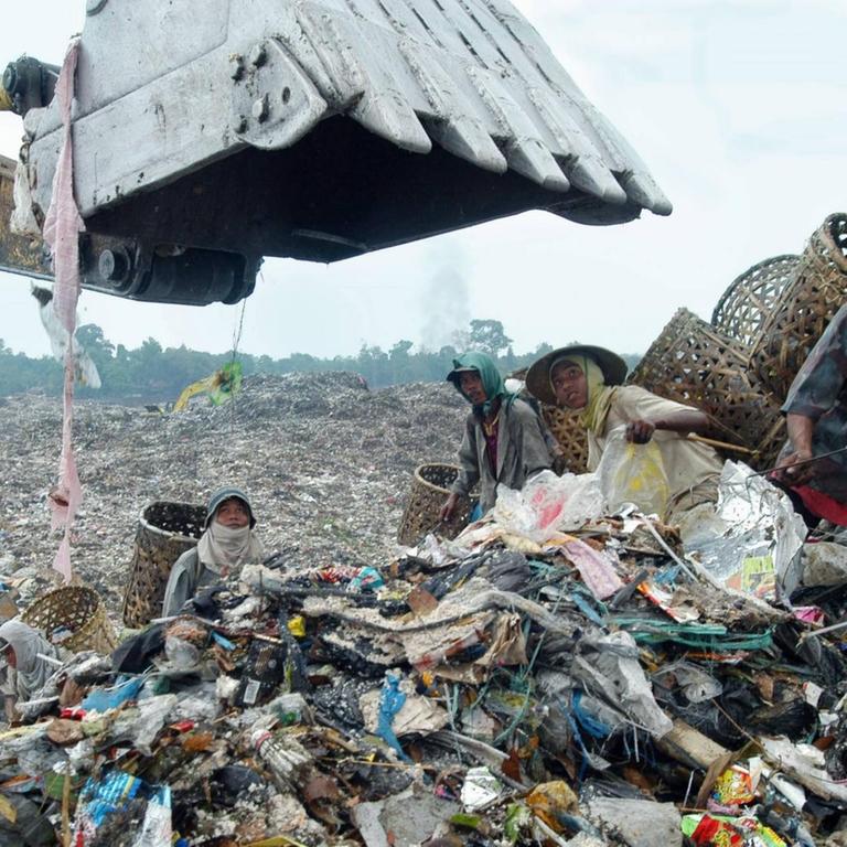 Straßenkinder stehen inmitten von Abfällen neben einem Bagger auf einer Müllhalde in Malaysia, Aufnahme geschätzt, ca. 2012