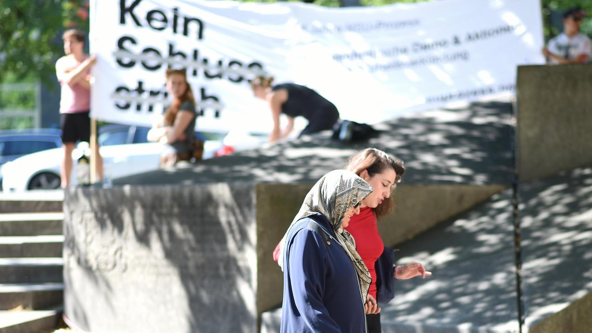 Die Tochter des ersten NSU-Mordopfers, Semiya Simsek (hinten) und ihre Mutter Adile kommen am 19.07.2017 zum Oberlandesgericht in München (Bayern), während im Hintergrund Aktivisten ein Plakat mit der Aufschrift "Kein Schlussstrich" halten. Vor dem Oberlandesgericht wurde der Prozess um die Morde und Terroranschläge des "Nationalsozialistischen Untergrunds" (NSU) fortgesetzt. Foto: Andreas Gebert/dpa | Verwendung weltweit Die Tochter des ersten NSU-Mordopfers, Semiya Simsek (hinten) und ihre Mutter Adile kommen am 19.07.2017 zum Oberlandesgericht in München (Bayern), während im Hintergrund Aktivisten ein Plakat mit der Aufschrift "Kein Schlussstrich" halten. Vor dem Oberlandesgericht wurde der Prozess um die Morde und Terroranschläge des "Nationalsozialistischen Untergrunds" (NSU) fortgesetzt. Foto: Andreas Gebert/dpa | Verwendung weltweit