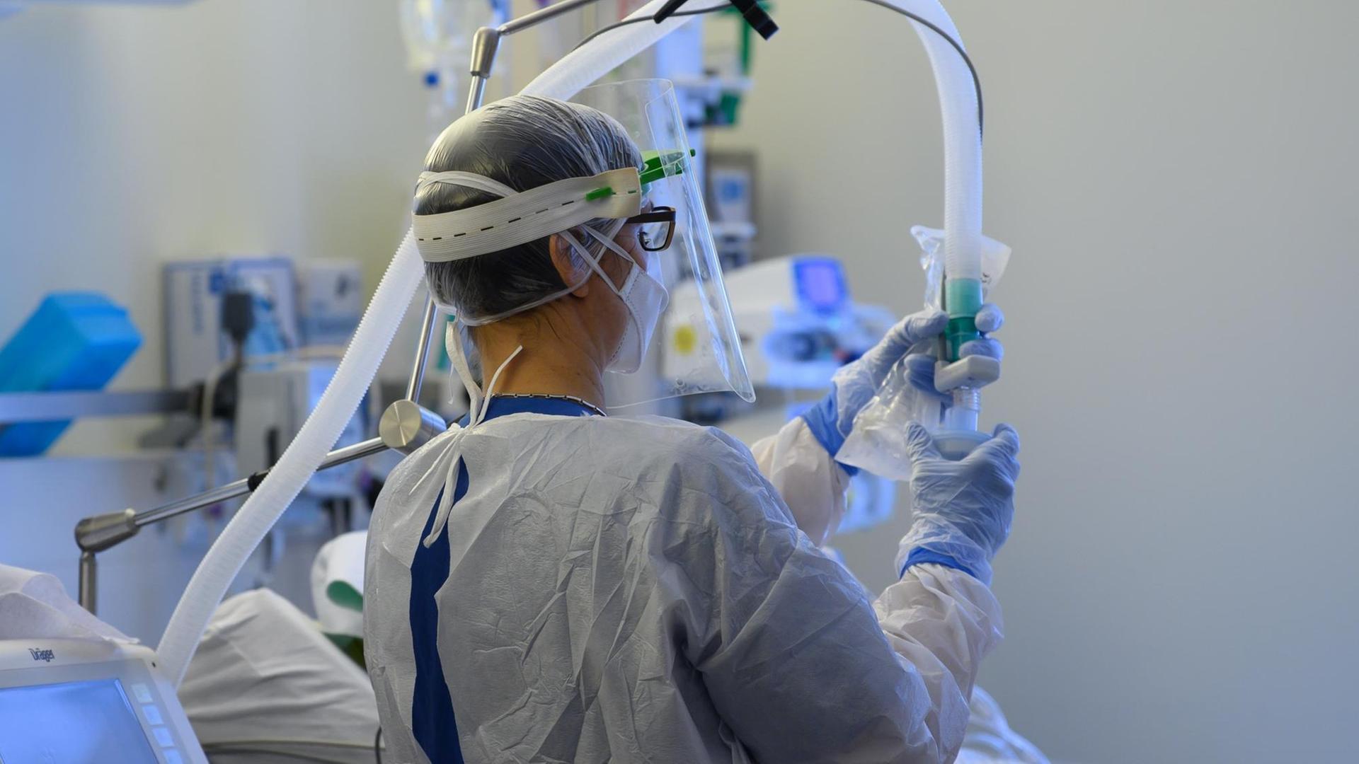 Eine Intensivpflegerin im Schutzanzug richtet auf der Covid-19 Intensivstation in der VAMED Klinik Schloss Pulsnitz einen Beatmungsschlauch ein.