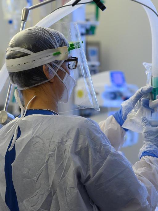 Eine Intensivpflegerin im Schutzanzug richtet auf der Covid-19 Intensivstation in der VAMED Klinik Schloss Pulsnitz einen Beatmungsschlauch ein.