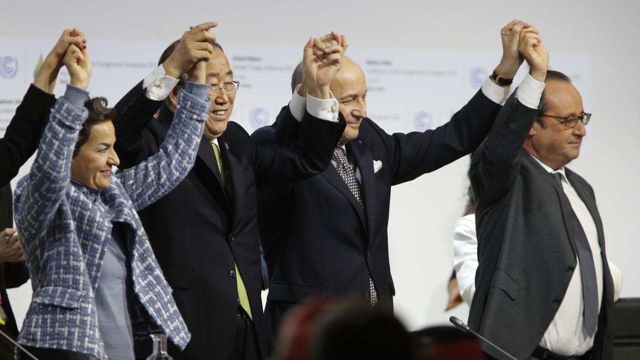 Teilnehmer der Klima-Konferenz halten sich an den Händen und recken sie in die Luft.