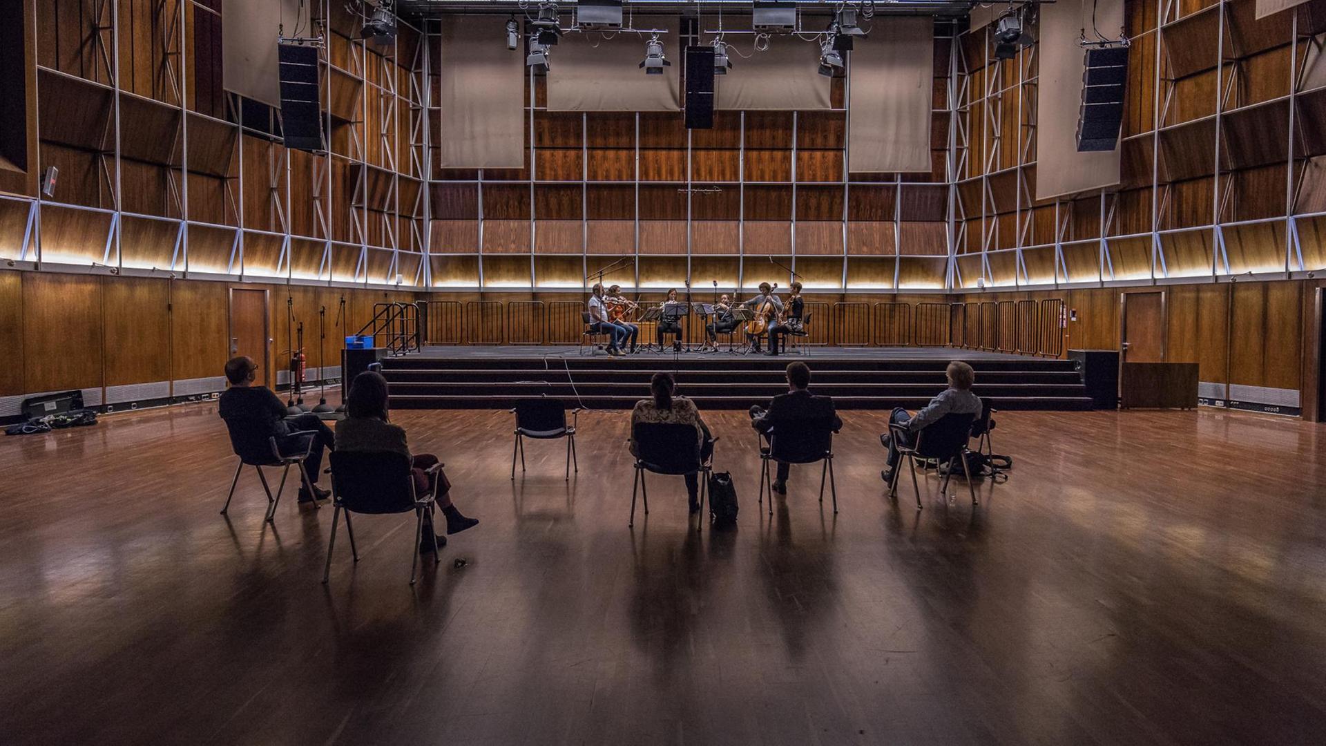 Musiker spielen auf der Bühne im holzgetäfelten Dlf Kammermusiksaal, im Raum vereinzelt fünf Zuhörer Musiker spielen auf der Bühne im holzgetäfelten Dlf Kammermusiksaal, im Raum vereinzelt fünf Zuhörer
