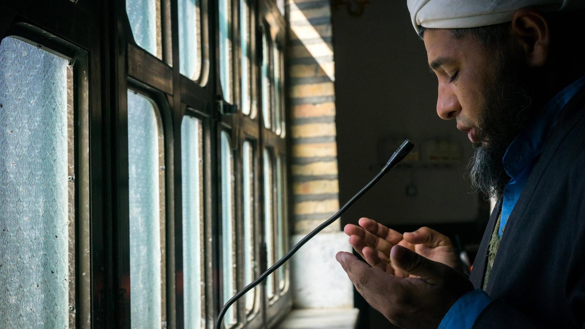 Ein Muezzin ruft über ein Mikrofon zum Gebet auf.