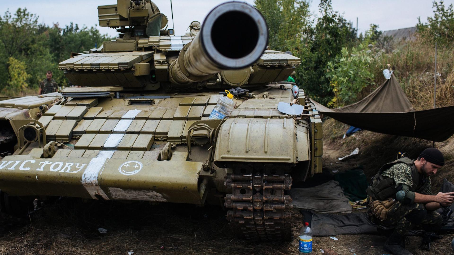 Ein ukrainischer Soldat sitzt neben einem Panzer im Osten der Ukraine. Ein ukrainischer Soldat sitzt neben einem Panzer im Osten der Ukraine.