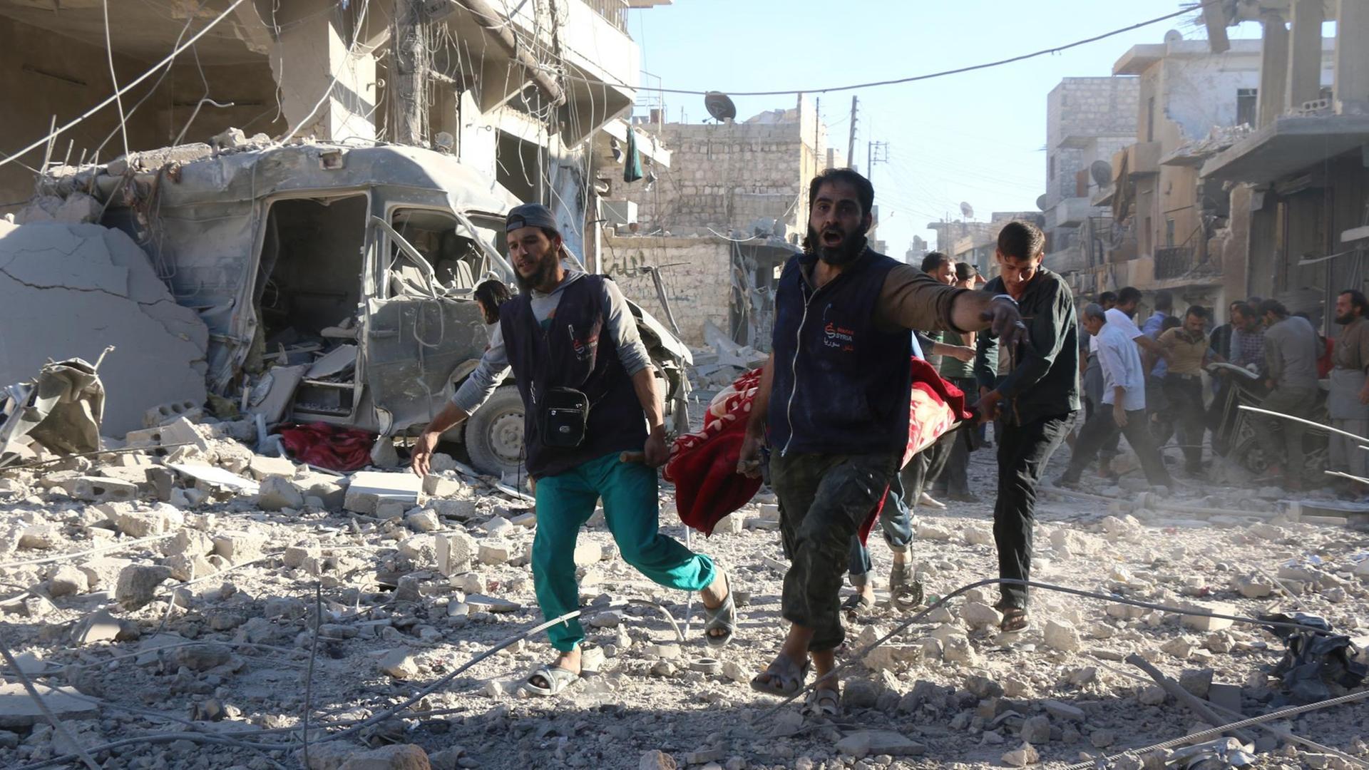 Syrer tragen nach einem Luftangriff der Regierungstruppen eine verletzte Person durch die zerstörten Straßen im Stadtteil Heluk in Aleppo. Syrer tragen nach einem Luftangriff der Regierungstruppen eine verletzte Person durch die zerstörten Straßen im Stadtteil Heluk in Aleppo.