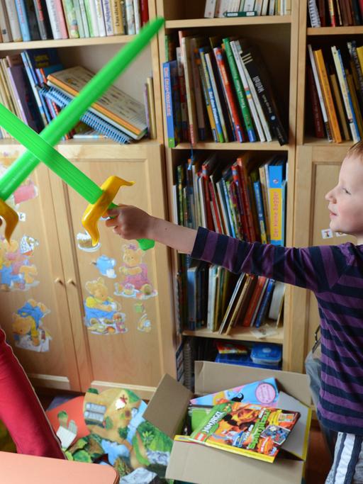 Ein achtjähriges Mädchen und ein fünfjähriger Junge "kämpfen" in ihrem Kinderzimmer mit Plastikschwertern gegeneinander.