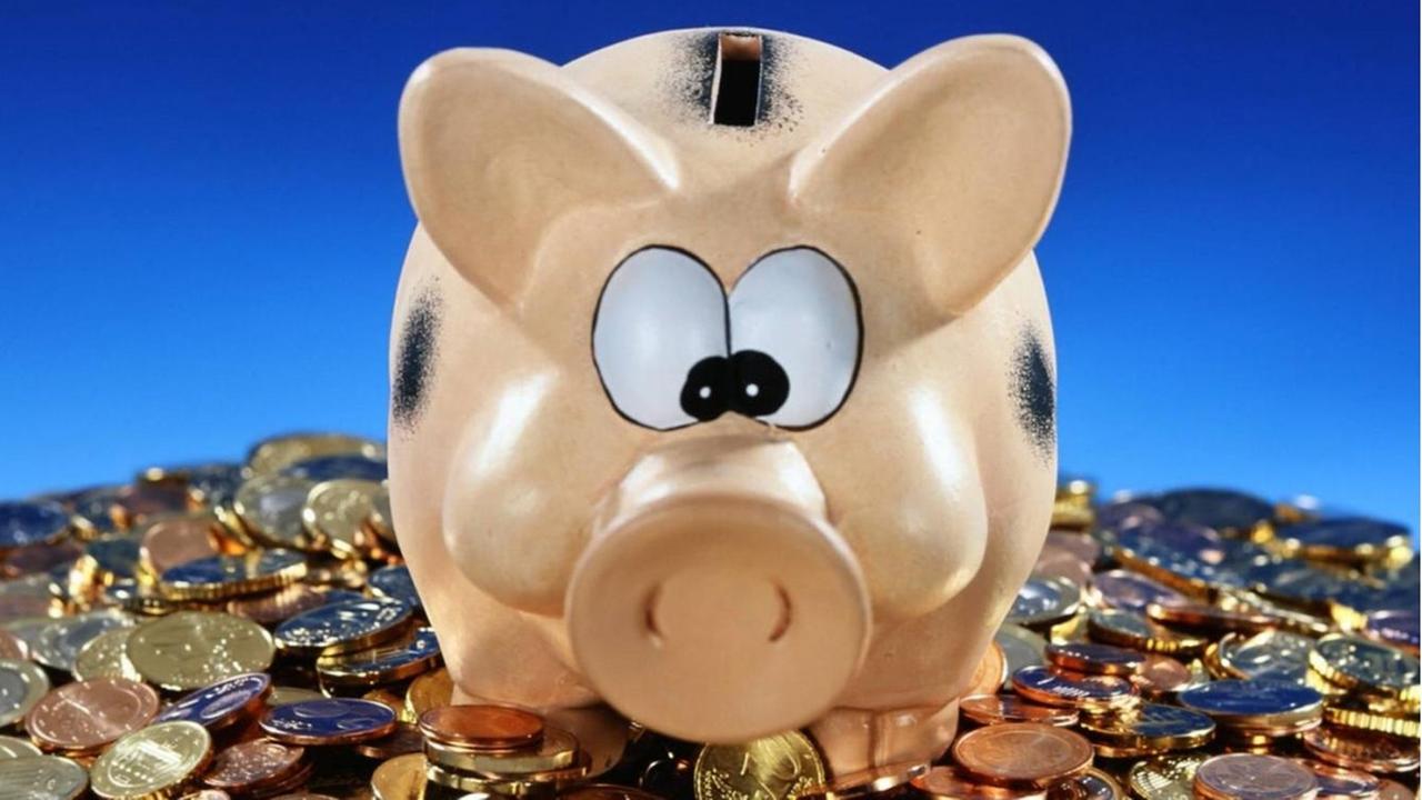 Ein Sparschwein steht auf einem Berg Münzen