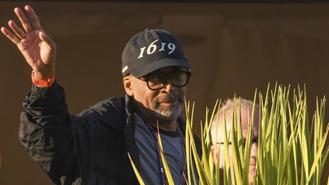 Der Regisseur und Jury-Präsident Spike Lee trägt eine schwarze Schirmmütze mit der Aufschrift "1619" und hebt die rechte Hand zum Gruß, als er zum Dinner der Jury bei den 74. Filmfestspielen von Cannes eintrifft.