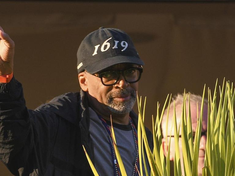 Der Regisseur und Jury-Präsident Spike Lee trägt eine schwarze Schirmmütze mit der Aufschrift "1619" und hebt die rechte Hand zum Gruß, als er zum Dinner der Jury bei den 74. Filmfestspielen von Cannes eintrifft.