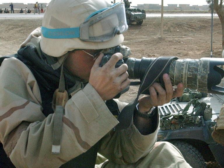 Einsatzbereit: Ein Kriegsfotograf sitzt mit seiner Kamera auf einem Panzer.