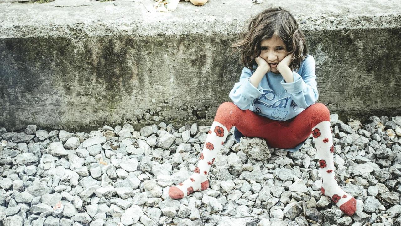 Ein Kind sitzt auf dem Bahnsteig im Bahnhof, Idomeni, Zentralmakedonien, Griechenland, Europa auf dem Boden.