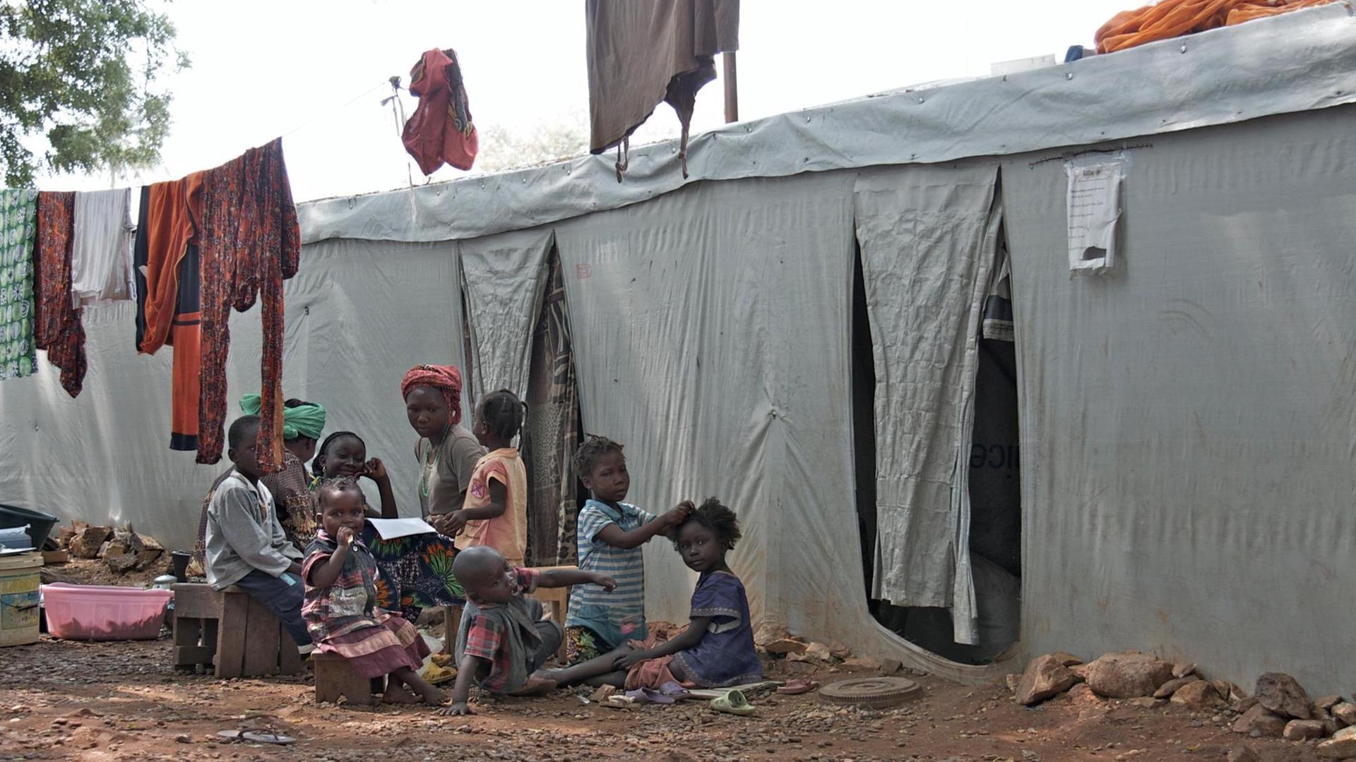 Obdachlose Flüchtlinge sitzen vor einer Notunterkunft in Bangui