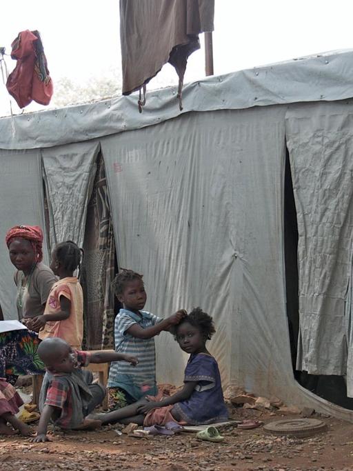 Obdachlose Flüchtlinge sitzen vor einer Notunterkunft in Bangui