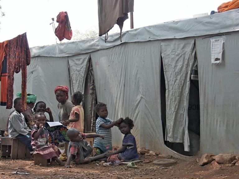 Obdachlose Flüchtlinge sitzen vor einer Notunterkunft in Bangui