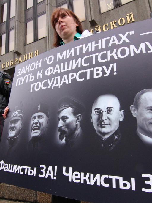 Demonstranten zeigen in Moskau ein Plakat mit Porträts von Adolf Hitler, Benito Mussolini, Felix Dzerzhinsky, Lavrenty Beria und Wladimir Putin.
