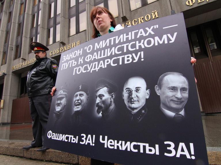 Demonstranten zeigen in Moskau ein Plakat mit Porträts von Adolf Hitler, Benito Mussolini, Felix Dzerzhinsky, Lavrenty Beria und Wladimir Putin.