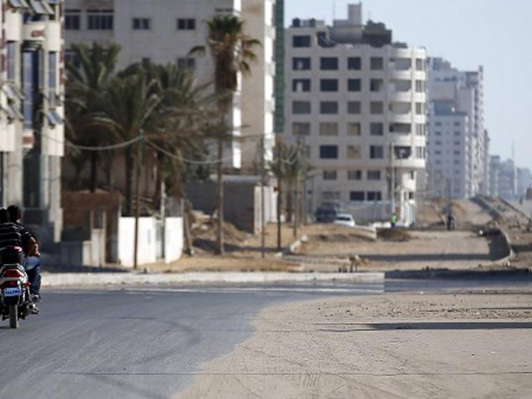 Palästinenser fahren mit einem Motorrad entlang einer ausgestorbenen Straße im Gaza-Streifen.