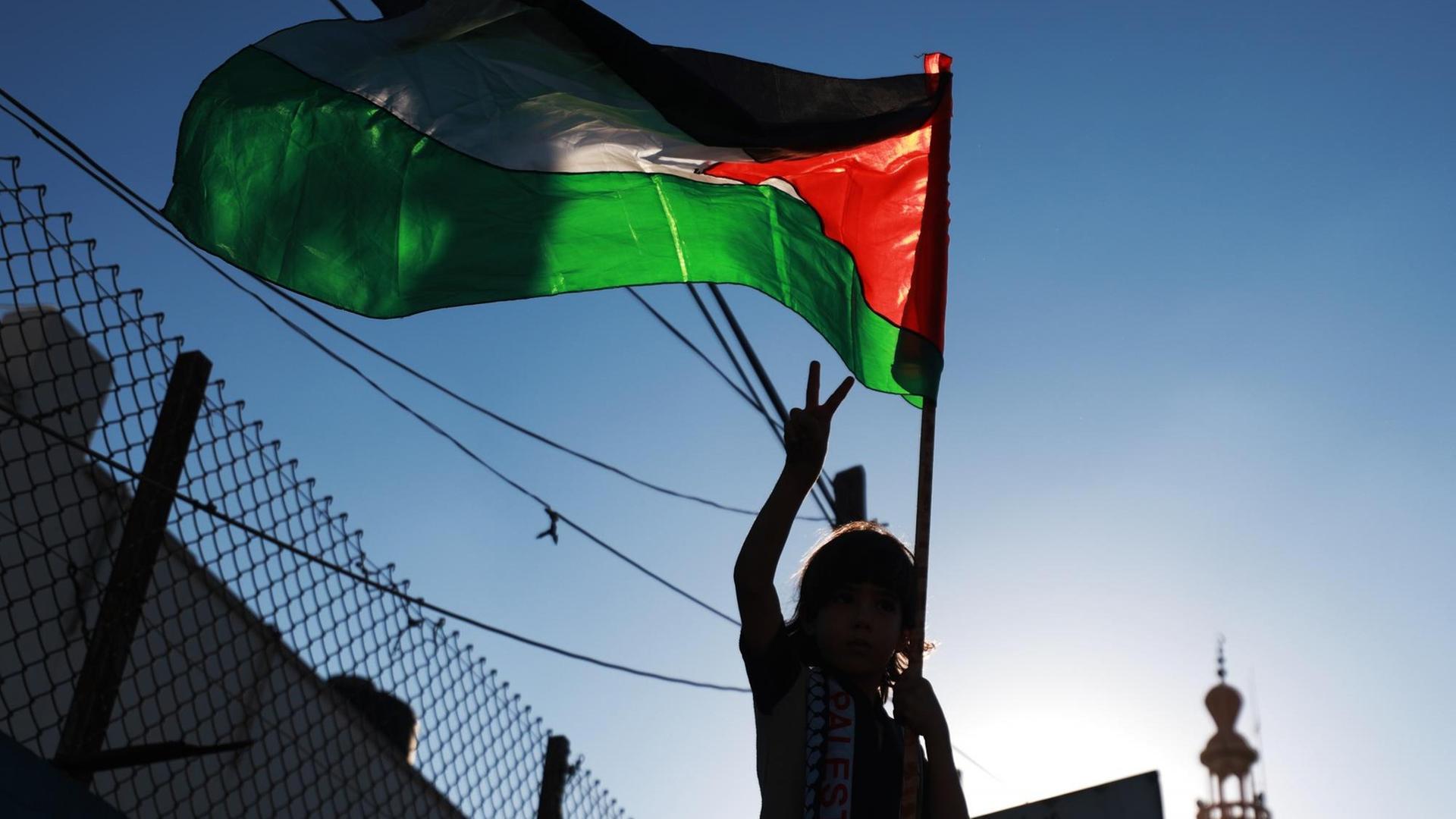 Bei Protesten gegen die Annexionspläne Israels ist in Gaza eine palästinensische Flage zu sehen. Ein Mädchen macht eine Siegesgeste. Bei Protesten gegen die Annexionspläne Israels ist in Gaza eine palästinensische Flage zu sehen. Ein Mädchen macht eine Siegesgeste.