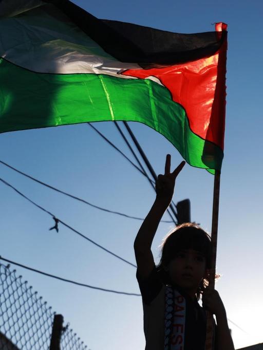Bei Protesten gegen die Annexionspläne Israels ist in Gaza eine palästinensische Flage zu sehen. Ein Mädchen macht eine Siegesgeste.