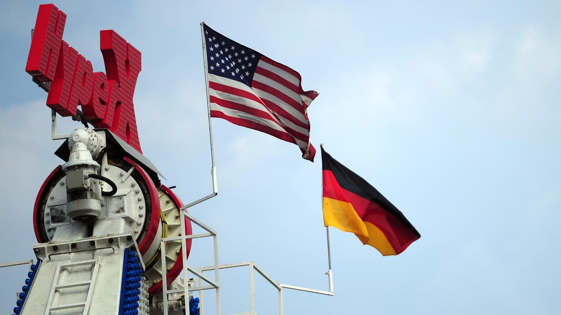 Eine deutsche und eine US-amerikanische Flagge wehen am 26.07.2013 auf dem Gelände des 53. Deutsch-Amerikanischen Volksfestes in Berlin an einem Fahrgeschäft. Eine deutsche und eine US-amerikanische Flagge wehen am 26.07.2013 auf dem Gelände des 53. Deutsch-Amerikanischen Volksfestes in Berlin an einem Fahrgeschäft.