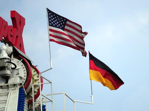 Eine deutsche und eine US-amerikanische Flagge wehen am 26.07.2013 auf dem Gelände des 53. Deutsch-Amerikanischen Volksfestes in Berlin an einem Fahrgeschäft.