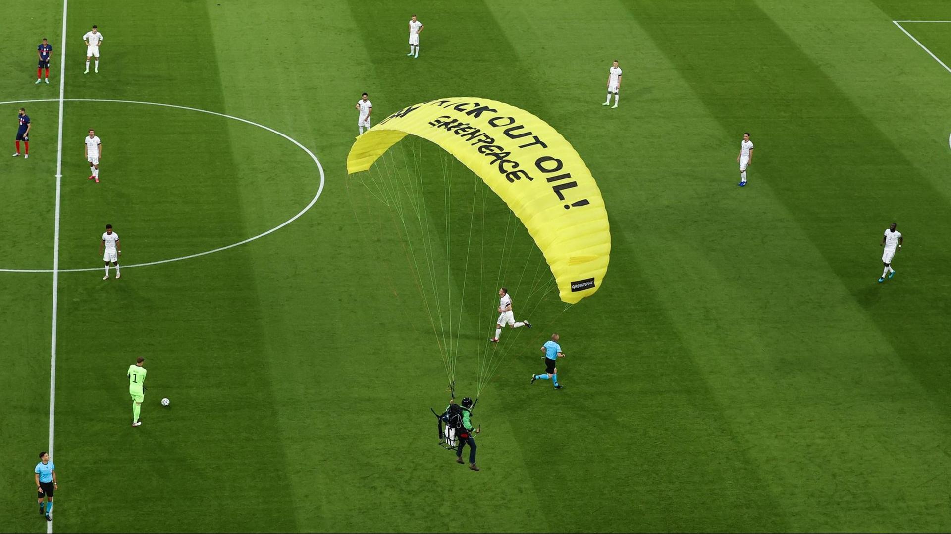 Das Foto zeigt, wie ein Greenpeace-Aktivist im Stadion von München landet.