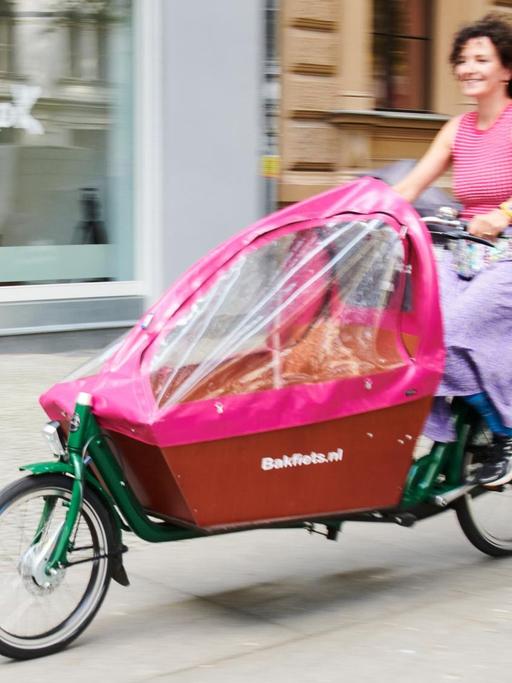 Eine Frau fährt mit einem Lastenrad durch Berlin.