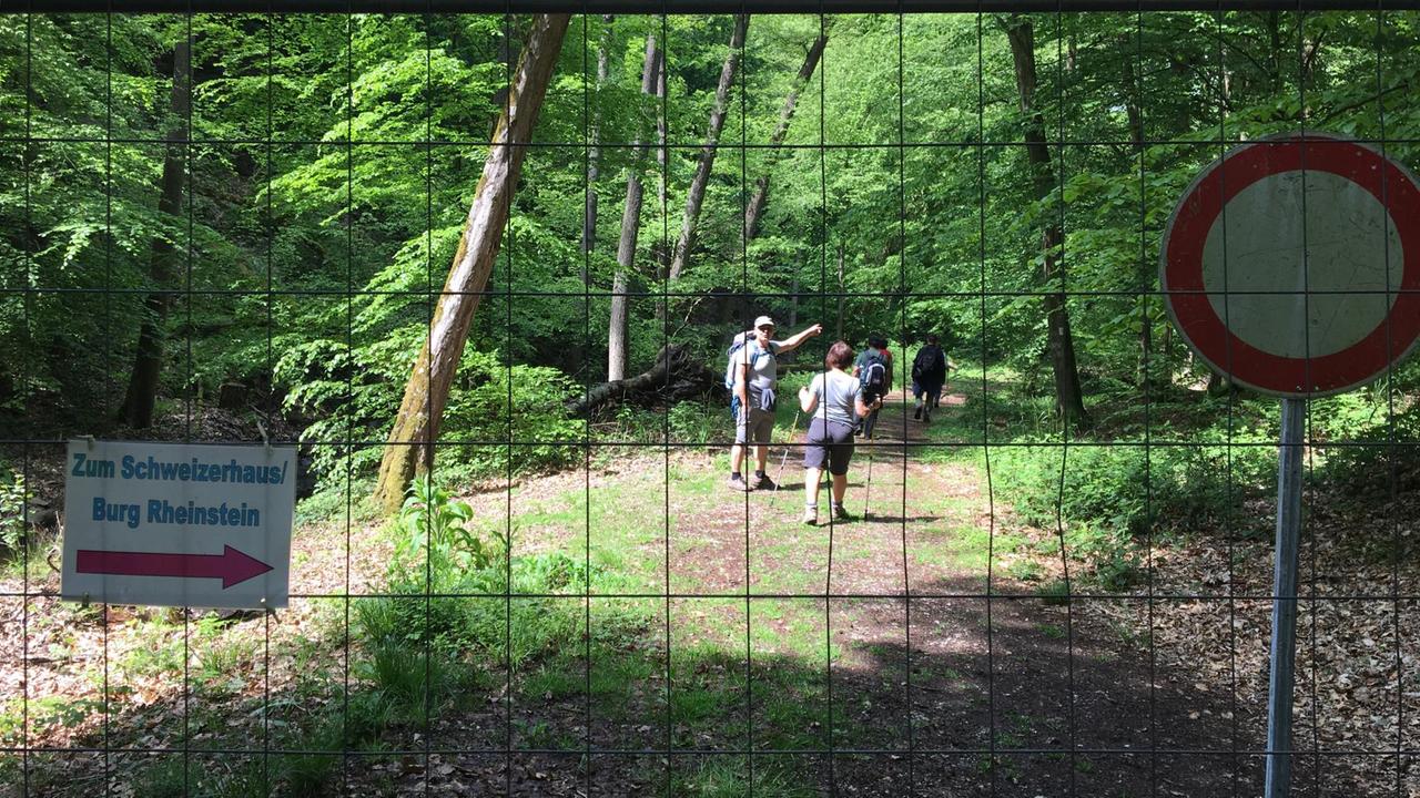 Wanderer hinter einem Zaun hinter dem auch ein Verbotsschild steht Wanderer hinter einem Zaun hinter dem auch ein Verbotsschild steht