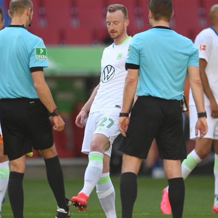 Wolfsburgs Maximilian Arnold verabschiedet sich nach dem Spiel von Assistent Dominik Schaal und Schiedsrichter Felix Brych mit einem Fußabklatschen.