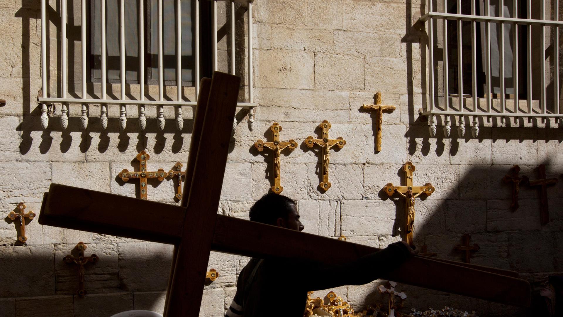 Ein palästinensischer Mann trägt ein Kreuz an den Beginn der Via Dolorosa in Jerusalem zurück. Ein palästinensischer Mann trägt ein Kreuz an den Beginn der Via Dolorosa in Jerusalem zurück.