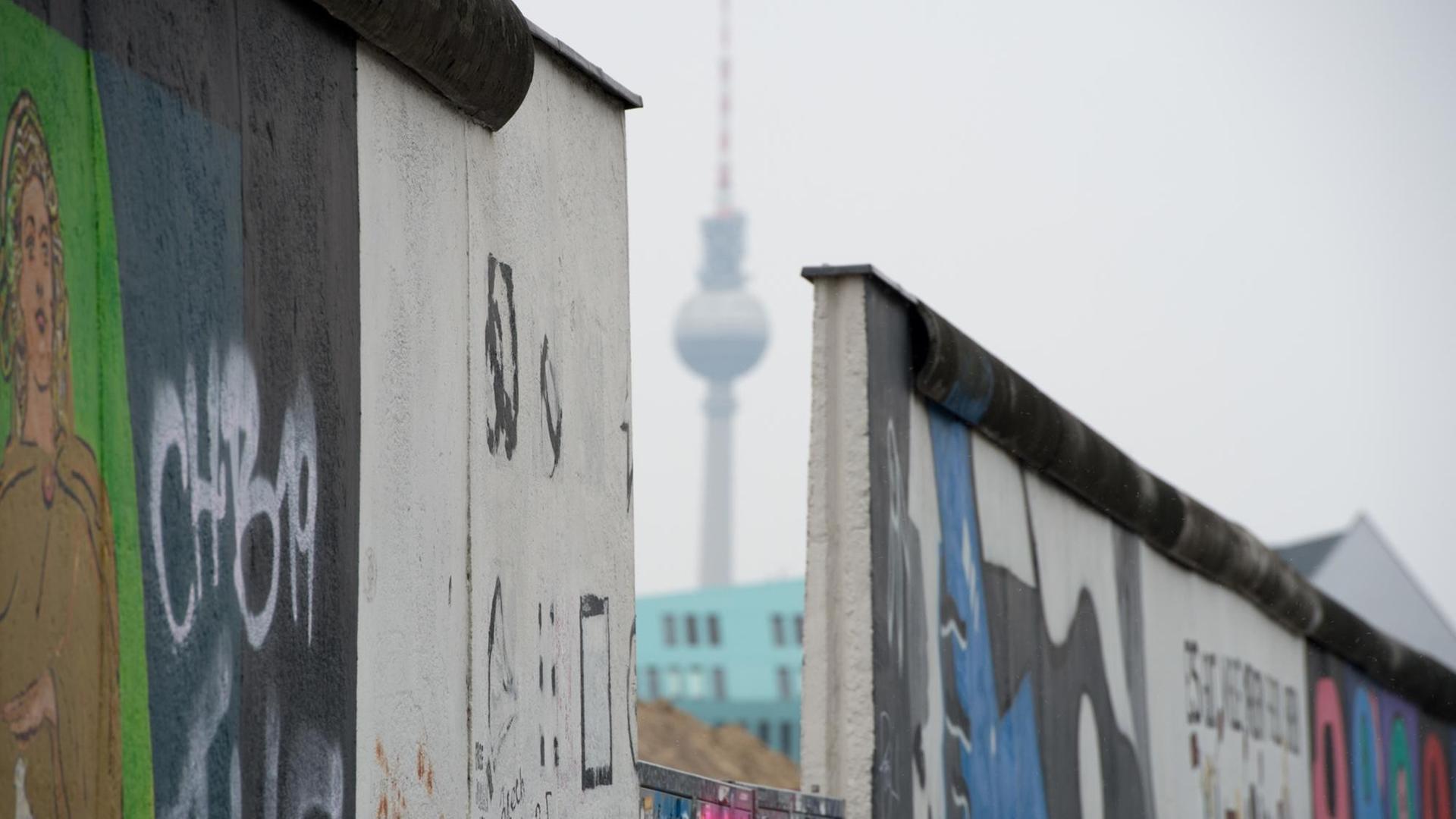 Der Fernsehturm ist am 09.03.2013 durch eine Lücke in der East Side Gallery in Berlin zu sehen. Die bunt bemalte Mauer ist das längste, erhaltene Stück der Berliner Mauer. Durchbrüche drohen das Denkmal immer mehr zu zerstören. Foto: Soeren Stache/dpa (Zu dpa-Korr.: «Kulturausschuss berät über Zukunft der East Side Gallery» vom 10.03.2013) | Verwendung weltweit Der Fernsehturm ist am 09.03.2013 durch eine Lücke in der East Side Gallery in Berlin zu sehen. Die bunt bemalte Mauer ist das längste, erhaltene Stück der Berliner Mauer. Durchbrüche drohen das Denkmal immer mehr zu zerstören. Foto: Soeren Stache/dpa (Zu dpa-Korr.: «Kulturausschuss berät über Zukunft der East Side Gallery» vom 10.03.2013) | Verwendung weltweit