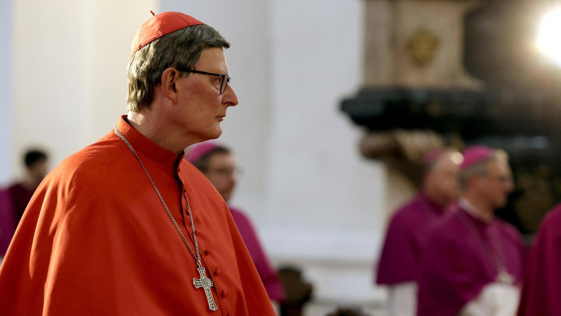 Kardinal Rainer Maria Woelki sitzt in einem roten Gewand in einem Raum und guckt traurig. Kardinal Rainer Maria Woelki sitzt in einem roten Gewand in einem Raum und guckt traurig.