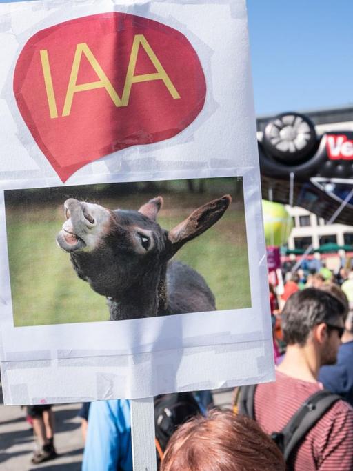 Demonstranten mit einem Plakat, auf dem ein Esel abgebildet ist mit einer Sprechblase, in der "IAA" geschrieben steht. 