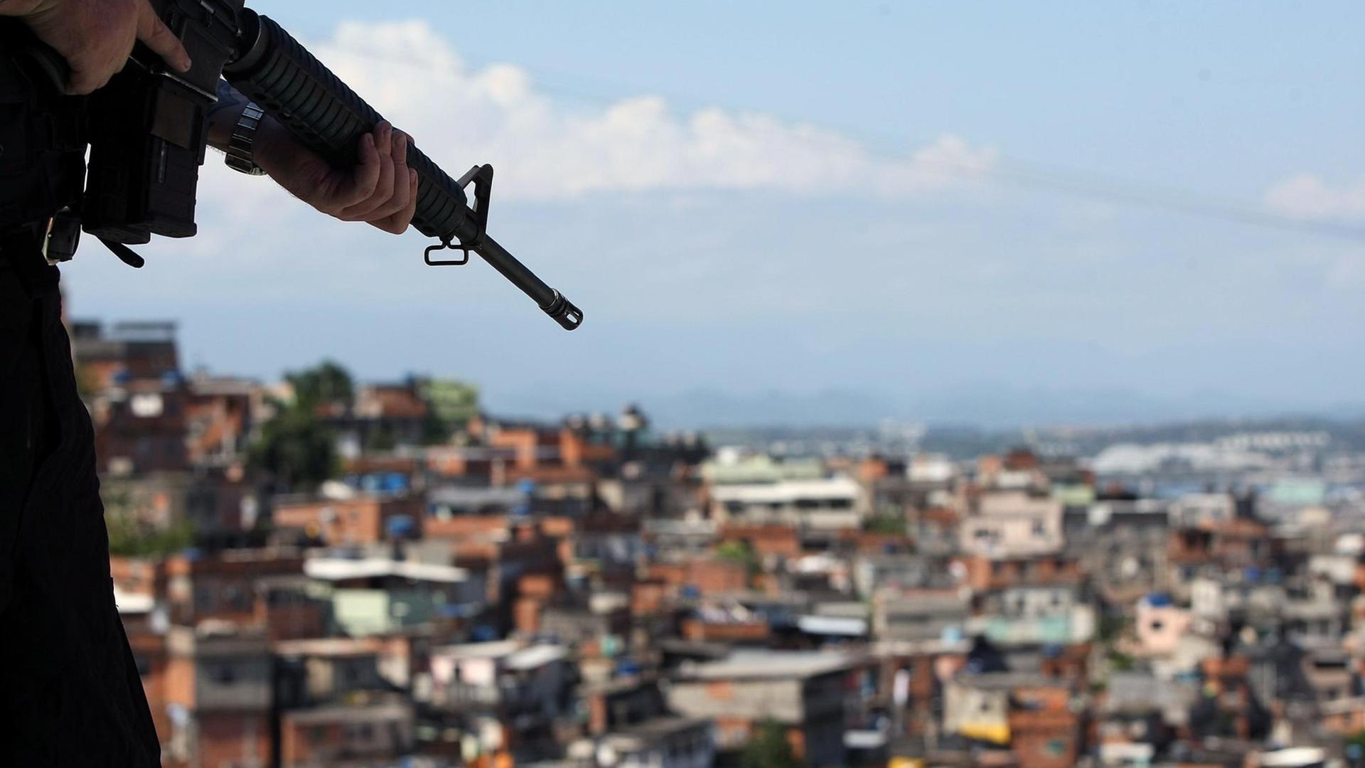 Ein brasilianischer Soldat hält ein Maschinengewehr in der Hand - im Hintergrund ist ein Armenviertel von Rio de Janeiro zu sehen. Ein brasilianischer Soldat hält ein Maschinengewehr in der Hand - im Hintergrund ist ein Armenviertel von Rio de Janeiro zu sehen.