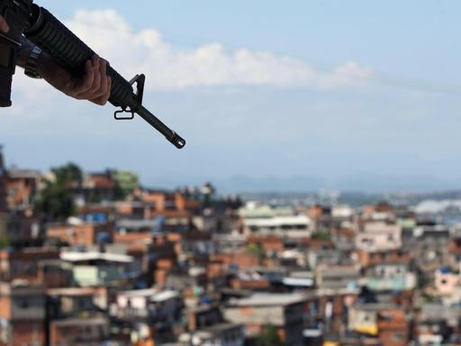Ein brasilianischer Soldat hält ein Maschinengewehr in der Hand - im Hintergrund ist ein Armenviertel von Rio de Janeiro zu sehen.