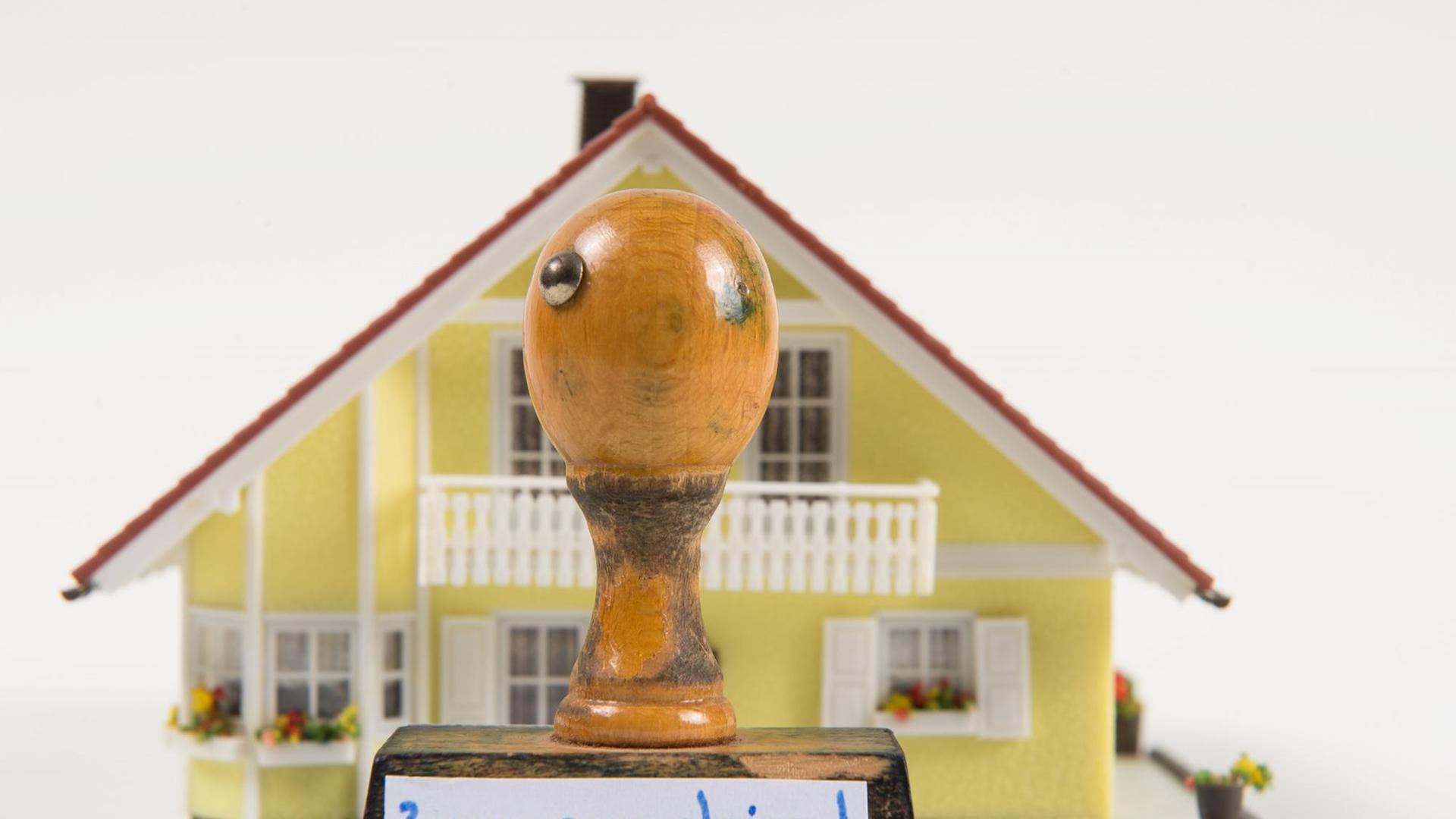 Symbolfoto zum Thema Zwangsversteigerung: Ein Modellhaus hinter einem Stempel mit der Aufschrift "zwangsversteigert". Symbolfoto zum Thema Zwangsversteigerung: Ein Modellhaus hinter einem Stempel mit der Aufschrift "zwangsversteigert".
