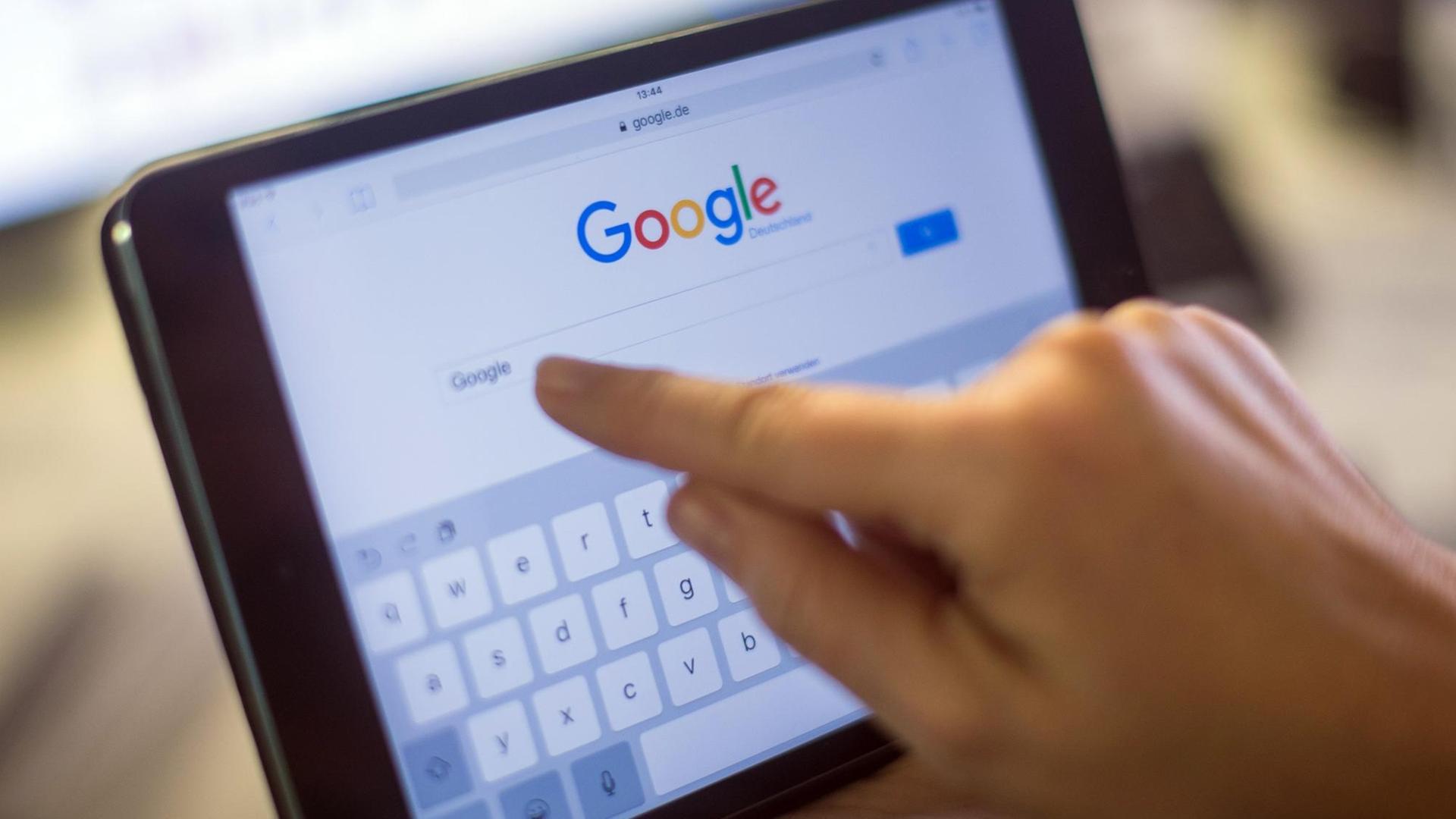 Ein Finger zeigt auf einem iPad auf das Google-Suchfeld. Ein Finger zeigt auf einem iPad auf das Google-Suchfeld.
