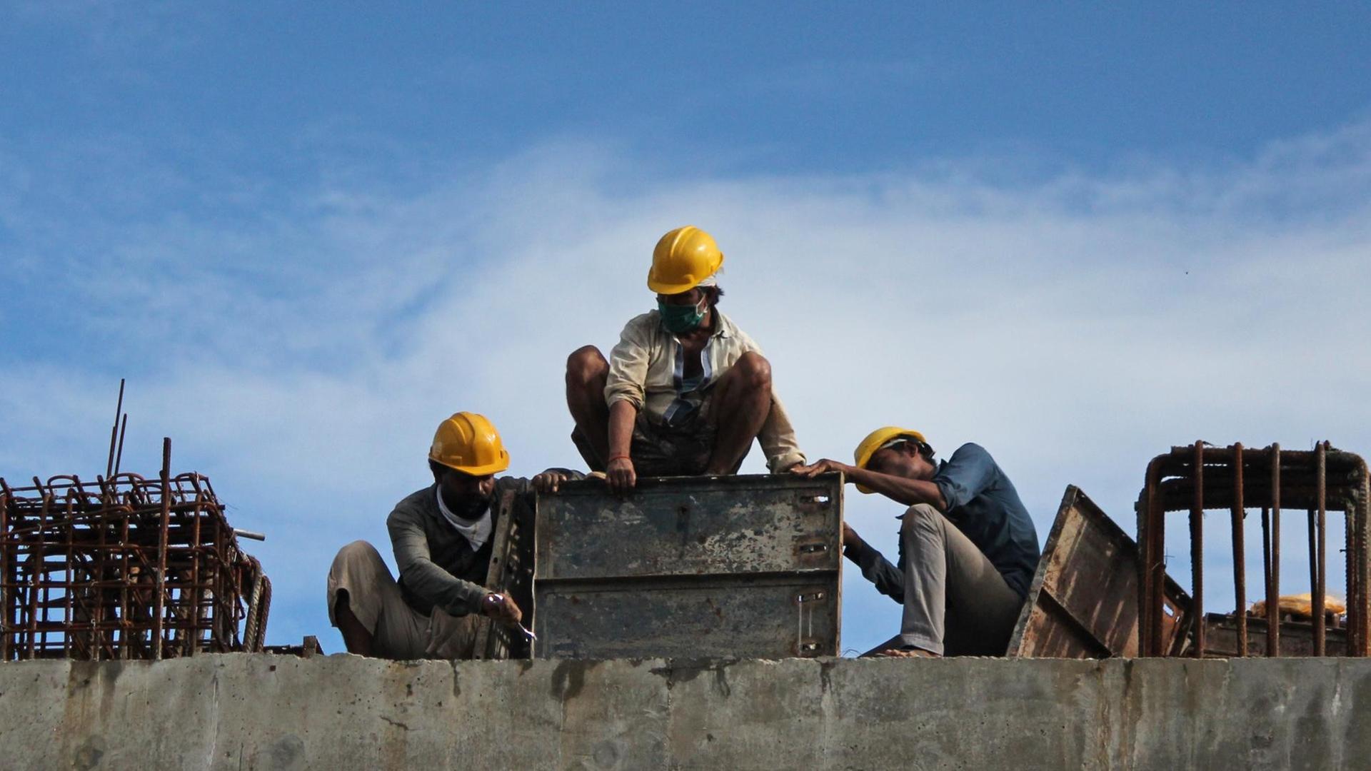 Blick auf eine Baustelle mit drei Arbeitern Blick auf eine Baustelle mit drei Arbeitern