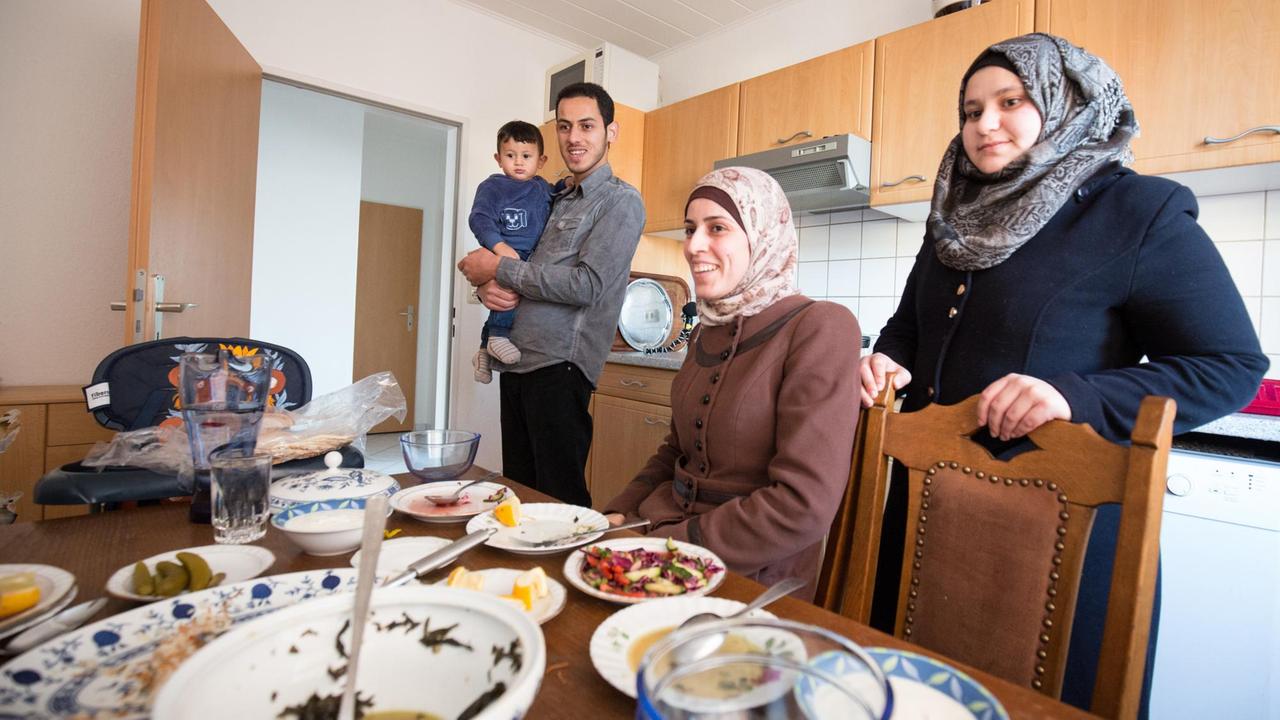 Die syrischen Flüchtlinge Hussein (mit Sohn Chalid), seine Frau Nadia (r) und seine Schwester Fatima stehen in Drochtersen (Niedersachsen) nach dem Mittagessen in der Küche der Wohnung von Hussein. 