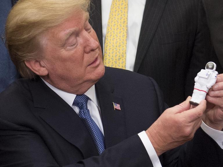 US-Präsident Donald Trump hält eine Astronauten-Figur in der Hand. 12 Amerikaner waren bereits auf dem Mond - bald sollen es nach dem Willen Trumps mehr werden.