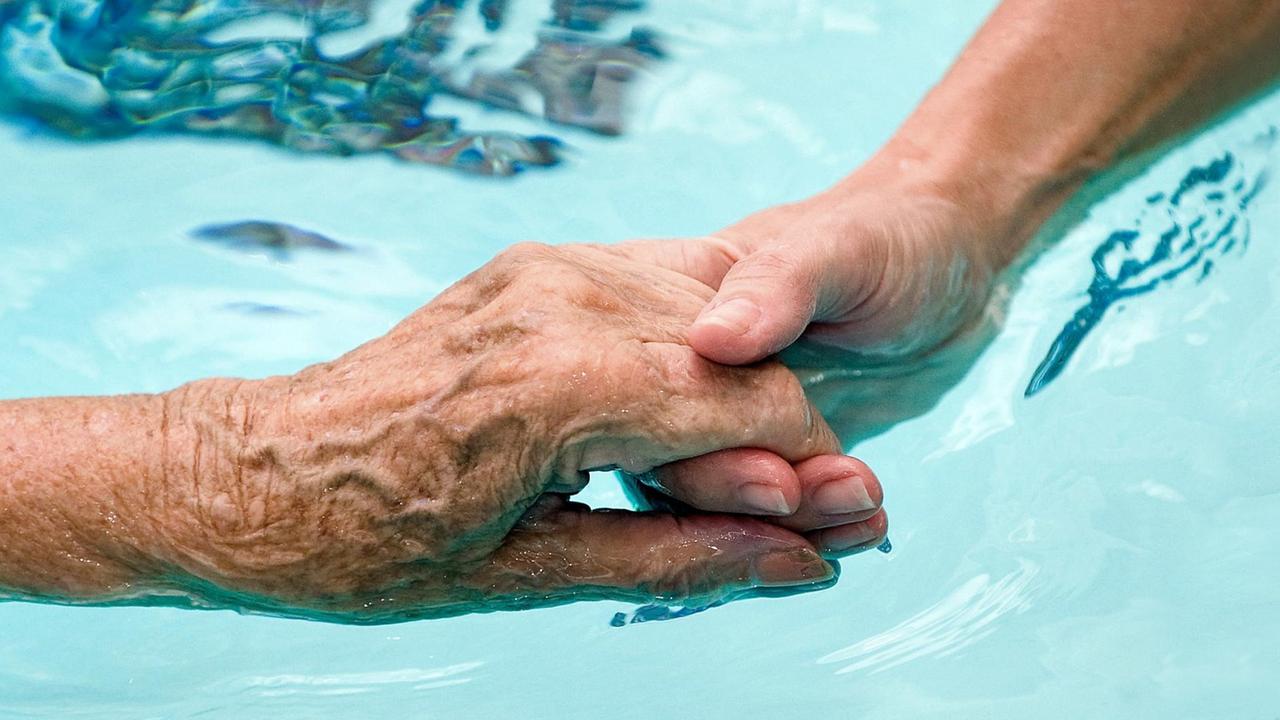 Nahaufnahme zweier sich haltender Hände im Wasser Nahaufnahme zweier sich haltender Hände im Wasser