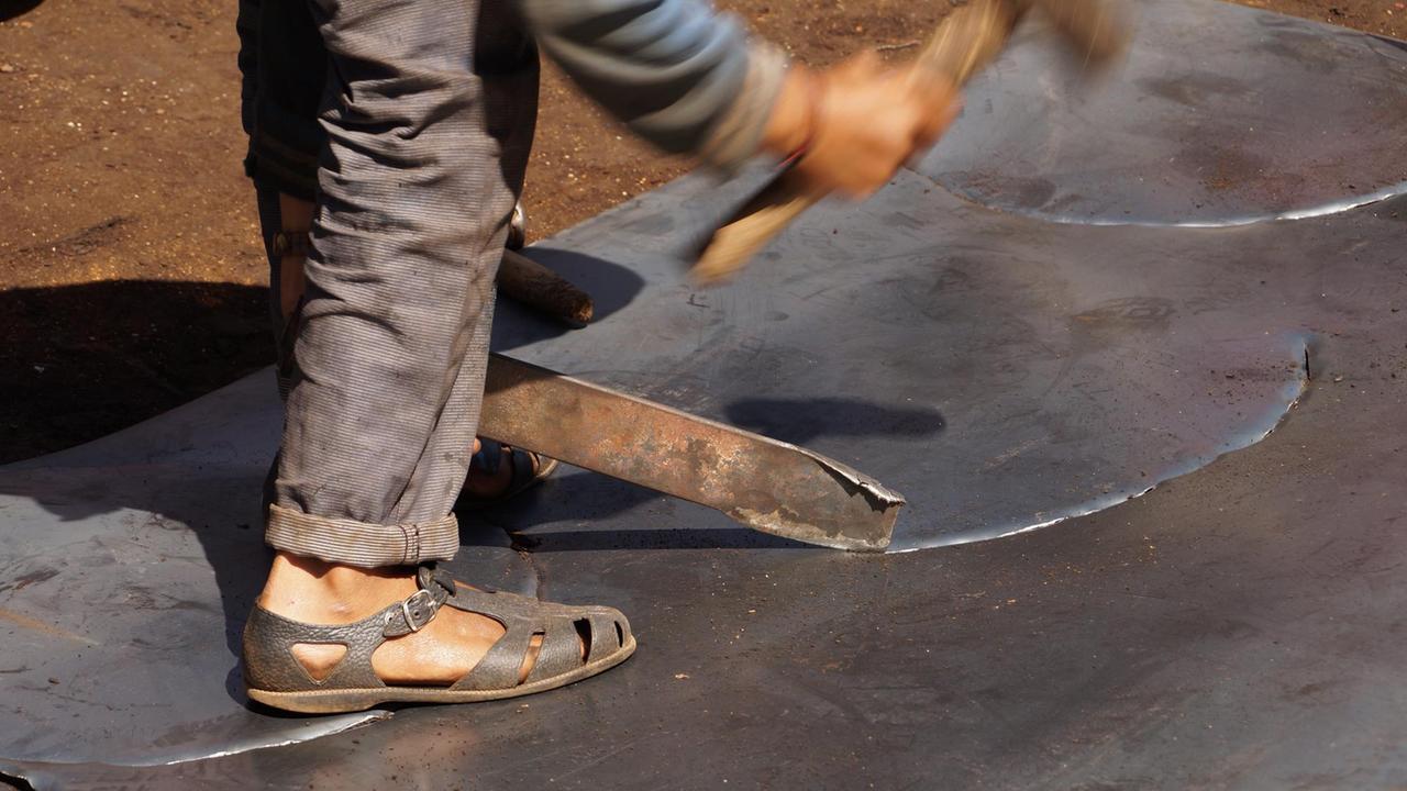 Ein Arbeiter hämmert auf Metall Ein Arbeiter hämmert auf Metall