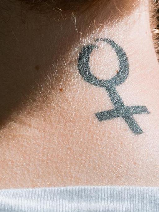 Eine Frau in Hamburg trägt das Frauenzeichen, den Venusspiegel, als Tattoo auf ihrem Nacken.