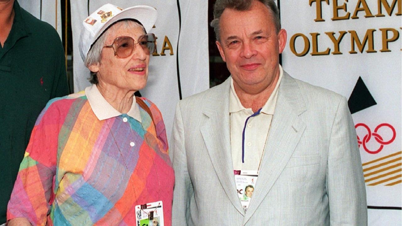 Margarete Bergmann-Lambert steht in buntem Sweatshirt an der Seite von NOK-Präsident Walther Tröger, der einen hellen Anzug trägt. Im Hintergrund ein Plakat mit dem Aufdruck Team Olympia. Margarete Bergmann-Lambert steht in buntem Sweatshirt an der Seite von NOK-Präsident Walther Tröger, der einen hellen Anzug trägt. Im Hintergrund ein Plakat mit dem Aufdruck Team Olympia.