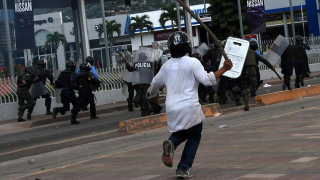 Soldaten und Polizeikräfte in Schutzkleidung flüchten vor den wütenden Anhängern des Oppositionsführers von Honduras, Salvador Nasralla. Die Demonstranten befinden sich in der Nähe des Wahlamtes von Tegucigalpa. Nasralla hatte seine Anhänger aufgefordert, auf die Straße zu gehen und seinen Sieg zu verteidigen.