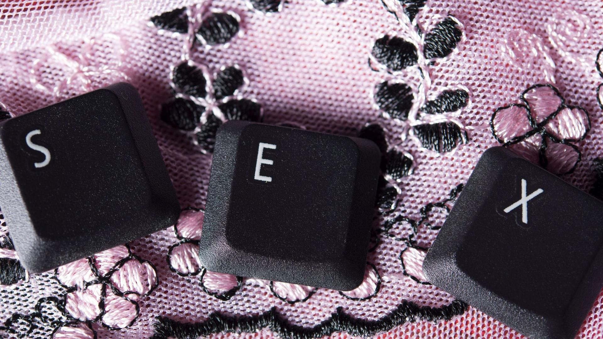 Die Tastatur-Buchstaben S, E, X liegen einzeln auf einer rosa Tischdecke. Die Tastatur-Buchstaben S, E, X liegen einzeln auf einer rosa Tischdecke.