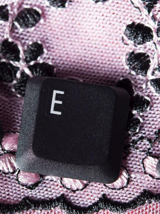 Die Tastatur-Buchstaben S, E, X liegen einzeln auf einer rosa Tischdecke.